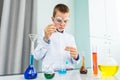 Child is doing chemical research work at home laboratory during distance learning Online courses. Smart little boy scientist.