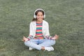 Child doing exercise on green grass. Healthy lifestyle and relax. Yoga girl. small kid wear headset. meditation summer Royalty Free Stock Photo