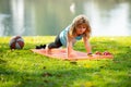 Child doing gymnastic exercises, sportive kid doing push ups on fitness mat in nature. Boy doing push-ups in the yard Royalty Free Stock Photo