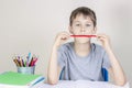 Kid doing homework at the table and thinking or dreaming