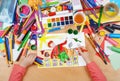 Child drawing boy fly with air on his back, top view hands with pencil painting picture on paper, artwork workplace