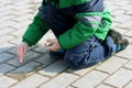 The child drawing with chalk on the pavement.