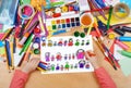 Child drawing cute happy cartoon people in row, top view hands with pencil painting picture on paper, artwork workplace