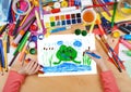 Child drawing frog in river, top view hands with pencil painting picture on paper, artwork workplace