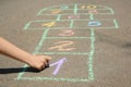 Child drawing hopscotch with colorful chalk on asphalt outdoors, closeup Royalty Free Stock Photo