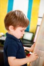 Child is drawing and painting with felt pen on paper of wooden drawing board artist easel for kids and children at home. Childhood Royalty Free Stock Photo