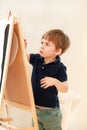 Child is drawing and painting with felt pen on paper of wooden drawing board artist easel for kids and children at home. Childhood Royalty Free Stock Photo