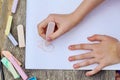 Child is drawing a picture on white paper with a colorful chalk Royalty Free Stock Photo