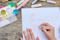 Child is drawing a picture on white paper with a colorful chalk Royalty Free Stock Photo