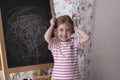 Child is drawing with pieces of color chalk on the chalk board. Girl is expressing creativity and looking at the camera Royalty Free Stock Photo