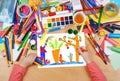 Child drawing rabbit with carrot on kitchengarden near house, top view hands with pencil painting picture on paper, artwork