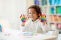 Child drawing rainbow. Paint on hands