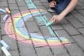 A child drawing a rainbow on the street with colored chalk. A child is playing outside Royalty Free Stock Photo