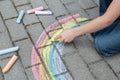 A child drawing a rainbow on the street with colored chalk. Selective focus. Kid. A child is playing outside Royalty Free Stock Photo