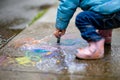 child drawing with wet chalk on sidewalk Royalty Free Stock Photo