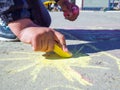 The child draws on the asphalt the sun