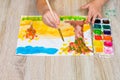 The child draws the autumn penzage with watercolors. Close-up of a child`s hand with a brush and watercolors. Children`s Royalty Free Stock Photo