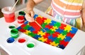 The child draws bright colorful puzzles with gouache. Drawing for World Autism Awareness Day. A creative child..