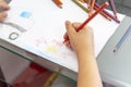 Child draws with colorful pencils. Children`s drawing on theme of fishing with goldfish, car