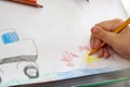 Child draws with colorful pencils. Children`s drawing on theme of fishing with goldfish, car