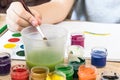 The child draws gouache on a white sheet and jars of paint are on the table. Hobbies and entertainment for children Royalty Free Stock Photo