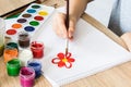 The child draws gouache on a white sheet and jars of paint are on the table. Hobbies and entertainment for children Royalty Free Stock Photo