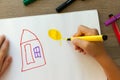 Child draws a pencil drawing of the peace. Green field, the bushes and the house