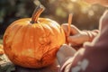 The child draws on the pumpkin, the child\'s hands close up. Halloween pumpkin with bokeh background. Jack O Lantern