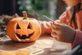 The child draws on the pumpkin, the child\'s hands close up. Halloween pumpkin with bokeh background. Jack O Lantern