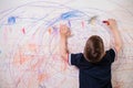 The child draws on the wall with a crayon. The boy is engaged in creativity at home Royalty Free Stock Photo
