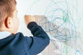 The child draws on the wall with a crayon. The boy is engaged in creativity at home Royalty Free Stock Photo