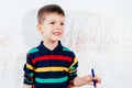 The child draws on the wall with a crayon. The boy is engaged in creativity at home Royalty Free Stock Photo