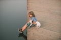 Child dreaming. Little kid embracing puppy dog, sitting near lake, childhood. Royalty Free Stock Photo