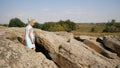 A child in a dress climbs rocks and stones.