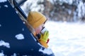 Child drinking hot chocolate or cocoa in sitting in black car at snowly winter day. Staycation tourism at winter time