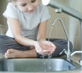 Child drinking water in kitchen at home. Thirsty baby. Hands open for drinking tap water. Pouring fresh drink. Water quality check Royalty Free Stock Photo