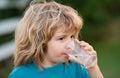 Child drinking water outdoor in park. Kid drinking. Close up portrait of boy drink water from glass in the garden. Royalty Free Stock Photo
