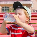 A child drinks water from a bottle. The child, the boy, quenches