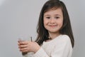 The child drinks water from a glass. A girl with dark hair holds a glass of water. The brunette leads a healthy