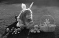 Child with easter eggs and bunny ears laying on grass. Funny boy, easter bunny kids.