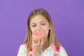 Child eat donut on violet background. Little girl bite glazed ring doughnut. Candyshop concept. Childhood and happiness