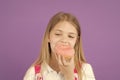 Child eat donut on violet background. Little girl bite glazed ring doughnut. Candyshop concept. Childhood and happiness