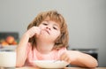 Child eat. Unhappy Caucasian child sit at table at home kitchen have no appetite. Upset little kid refuse to eat organic Royalty Free Stock Photo