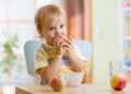 Child eating apple at dinner in nursery at home