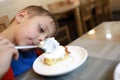 Child eating cheesecake with sour cream