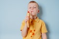 A child eating a French hot dog and stains his clothes with a ketchup stain. place for text