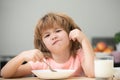 Child eating healthy food at home. Unhappy Caucasian child sit at table at home kitchen have no appetite. Upset little Royalty Free Stock Photo