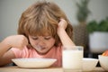 Child eating healthy food at home. Unhappy child have no appetite. Upset little kid refuse to eat organic cereals with Royalty Free Stock Photo