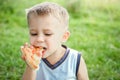 child eating a tasty pizza on the nature of the grass in the park