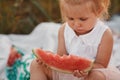 Child eating watermelon in the garden. Little girl playing in the garden holding a slice of water melon. Kid gardening Royalty Free Stock Photo